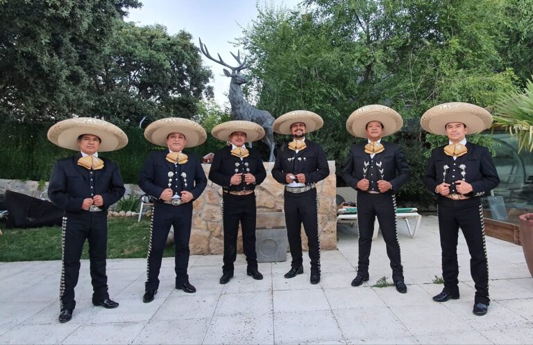 Siete mariachis de Mariachi Toluca con traje negro y sombrero en el jardín de una boda