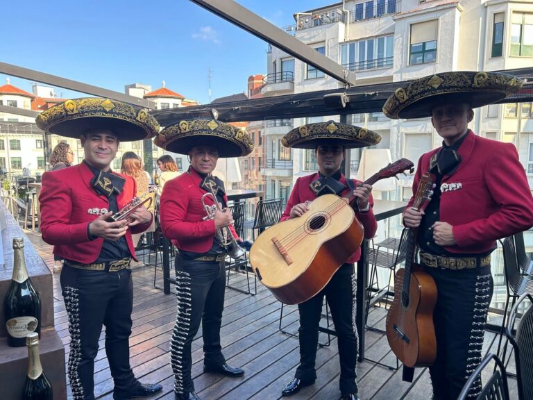 Mariachi Toluca con chaqueta roja tocando en una terraza con vistas al mar